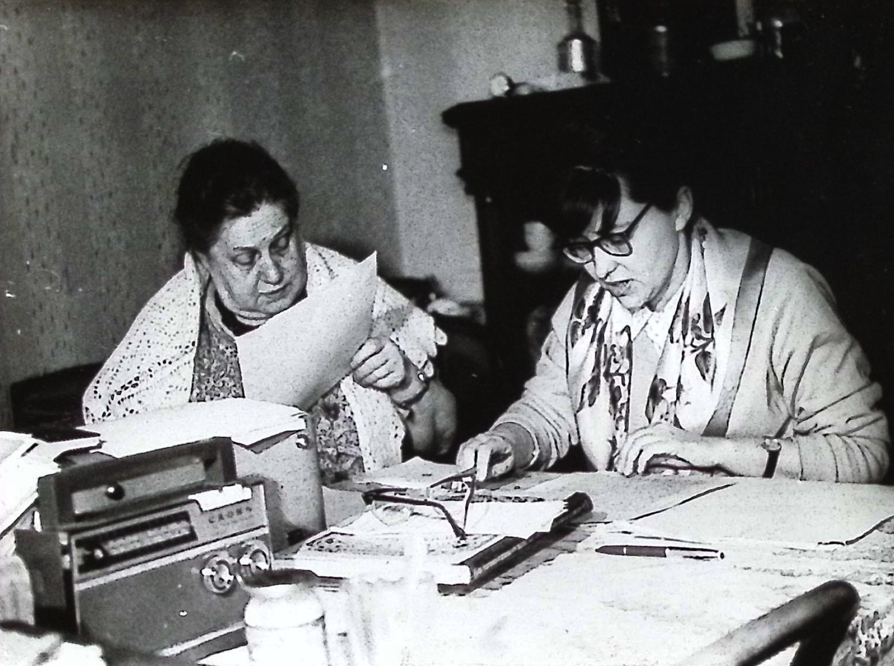 Voinova with an assistant, working through a set of sheets at the dining table.